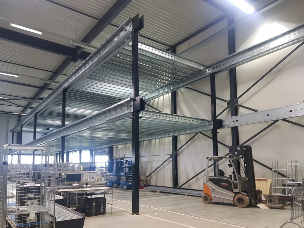 Montage van stalen structuur met liggers voor toekomstige tussenvloer in lege industriële hal.